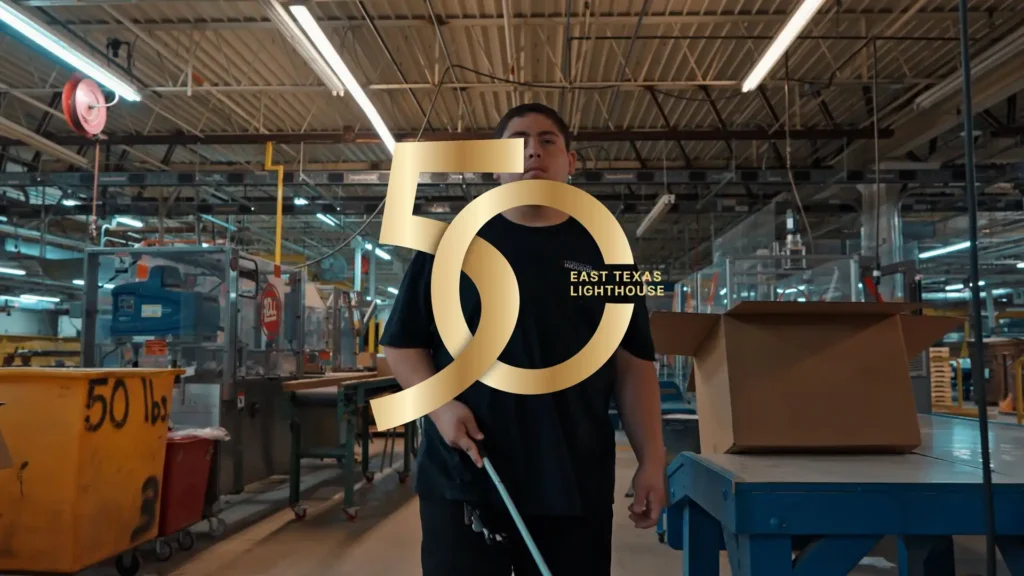 young blind man walking with can at a manufacturing plant with the numbers 50 in front of him