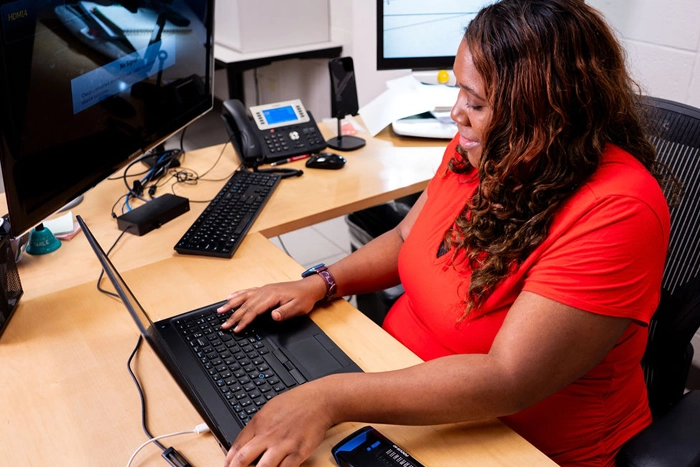 image of blind woman working at her desk on a computer at East Texas Lighthouse for the Blind