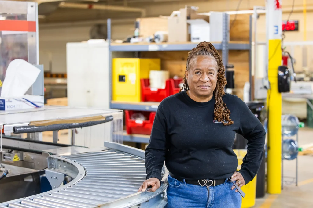 African American worker at Horizon Industries plant in front of conveyor belt