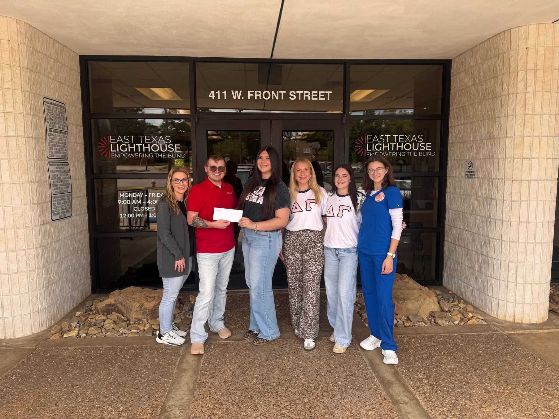 Delta Gamma members from UT Tyler presenting a donation check outside East Texas Lighthouse for the Blind.